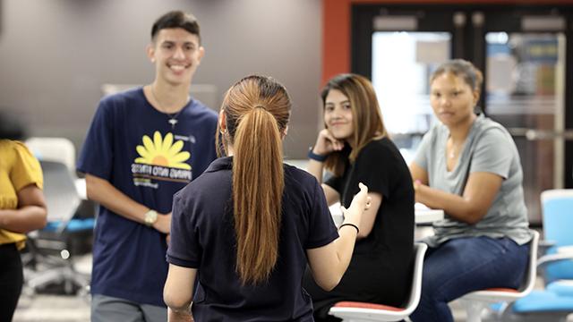 An admissions rep talks to a group of prospective students in the student engagement center